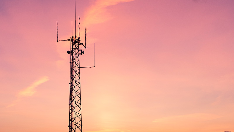 Torre de telecomunicaciones en un campo abierto al atardecer